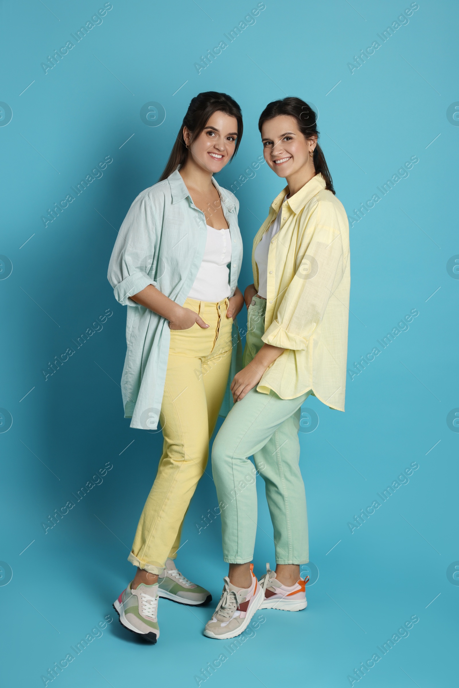 Photo of Portrait of beautiful twin sisters on light blue background