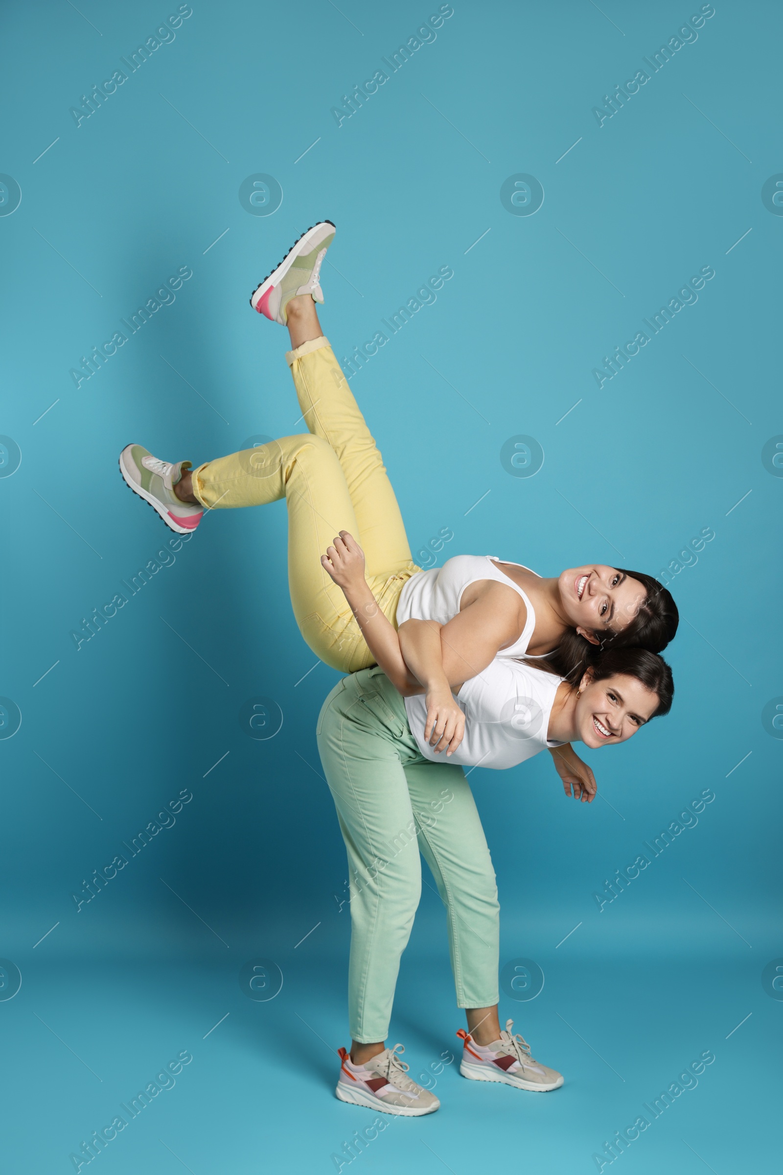 Photo of Beautiful twin sisters having fun on light blue background