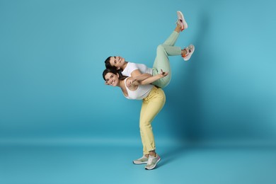 Photo of Beautiful twin sisters having fun on light blue background