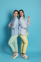 Photo of Portrait of beautiful twin sisters on light blue background