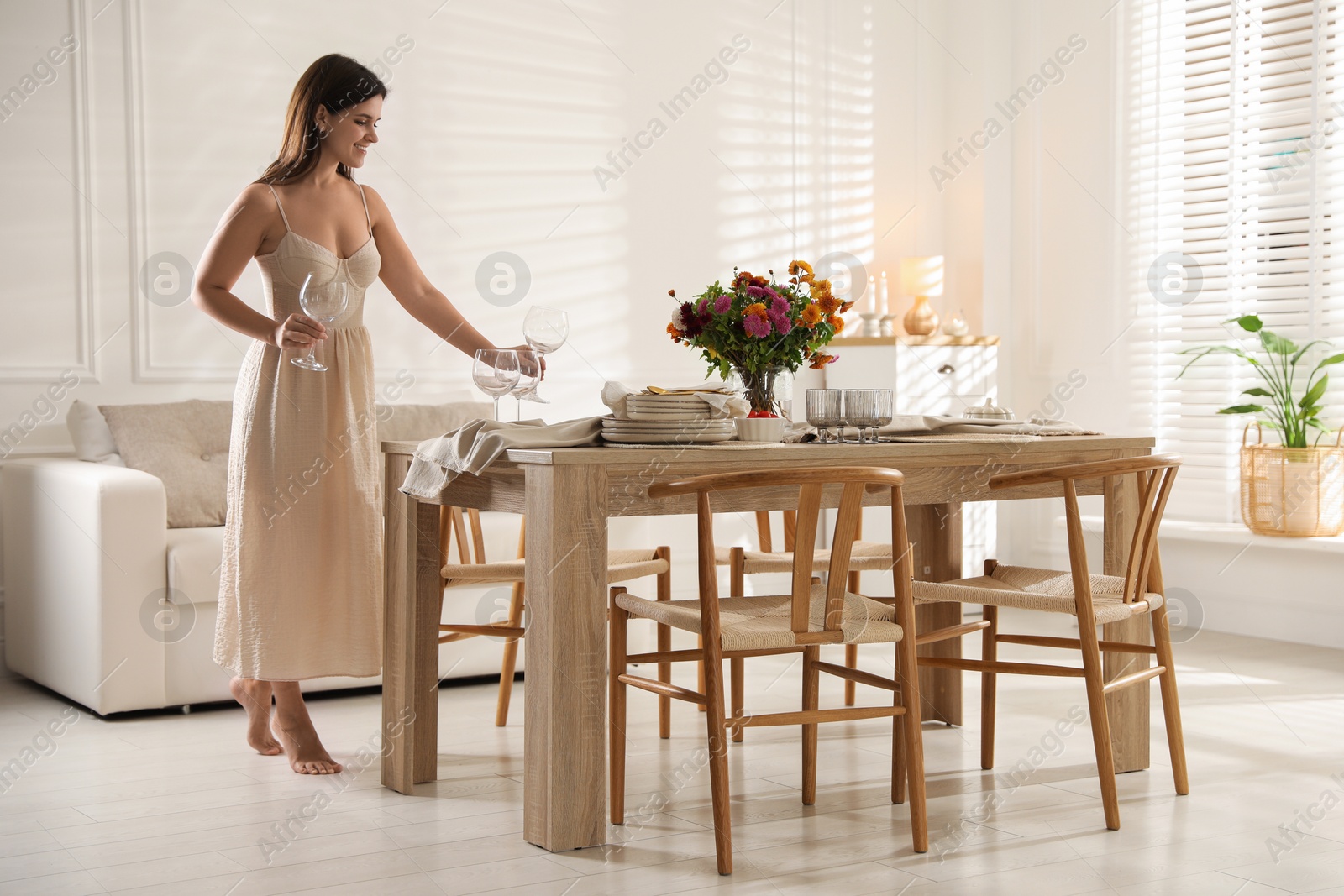 Photo of Woman setting table for dinner at home