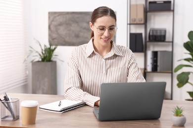 Photo of Programmer working on laptop at wooden desk indoors