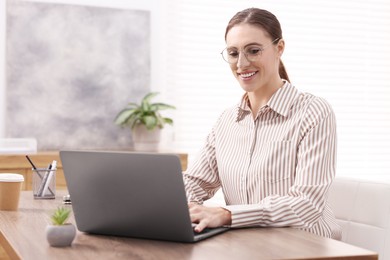 Photo of Programmer working on laptop at wooden desk indoors