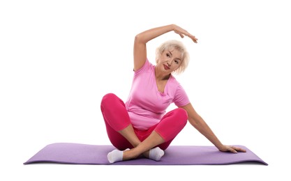 Senior woman exercising with fitness mat on white background