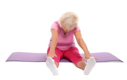 Photo of Senior woman exercising with fitness mat on white background