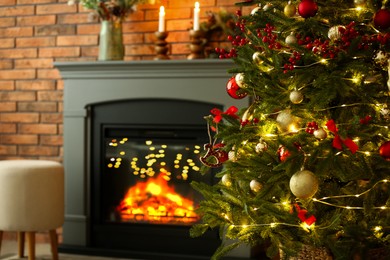 Photo of Beautiful decorated Christmas tree near fireplace at home, closeup. Space for text