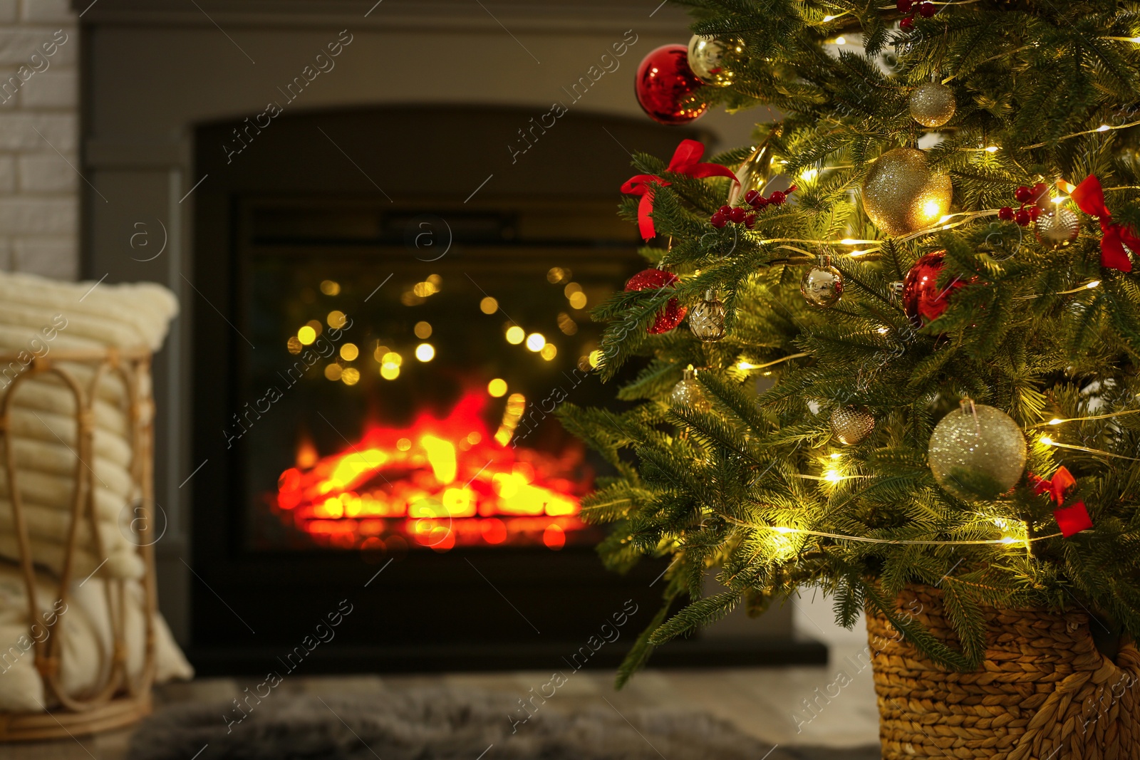 Photo of Beautiful decorated Christmas tree near fireplace at home, closeup. Bokeh effect