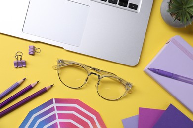 Photo of Designer's workplace. Flat lay composition with stationery and laptop on yellow background