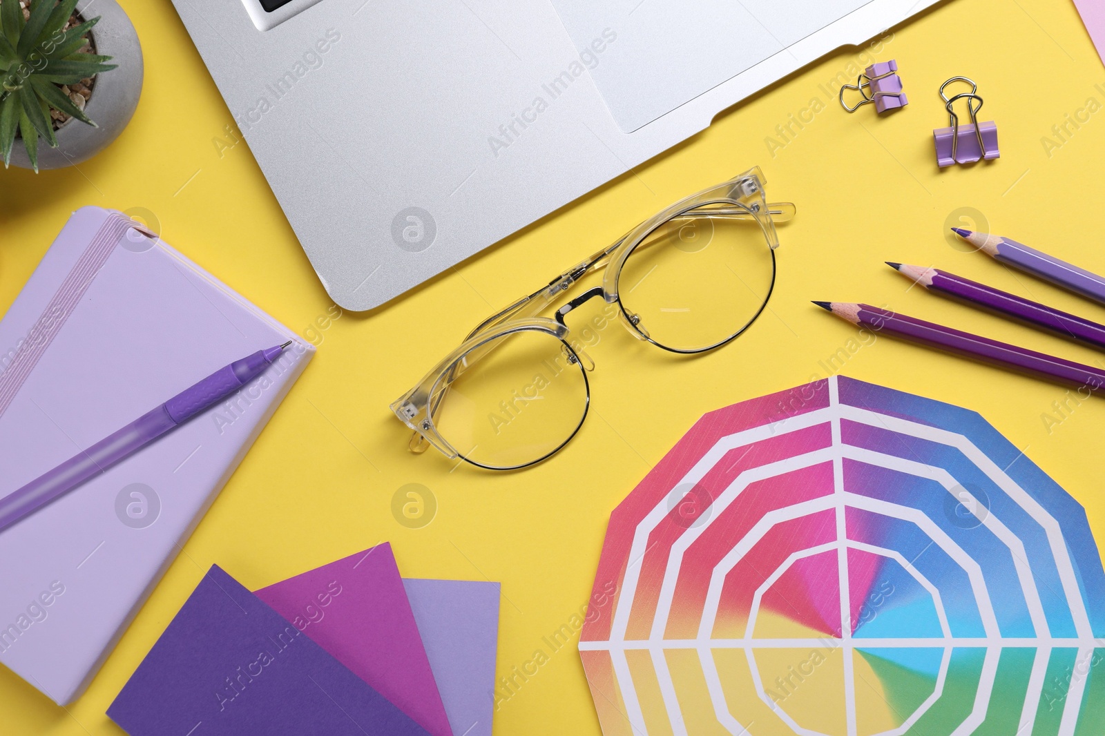 Photo of Designer's workplace. Flat lay composition with stationery and laptop on yellow background