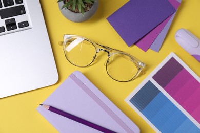 Photo of Designer's workplace. Flat lay composition with stationery and laptop on yellow background