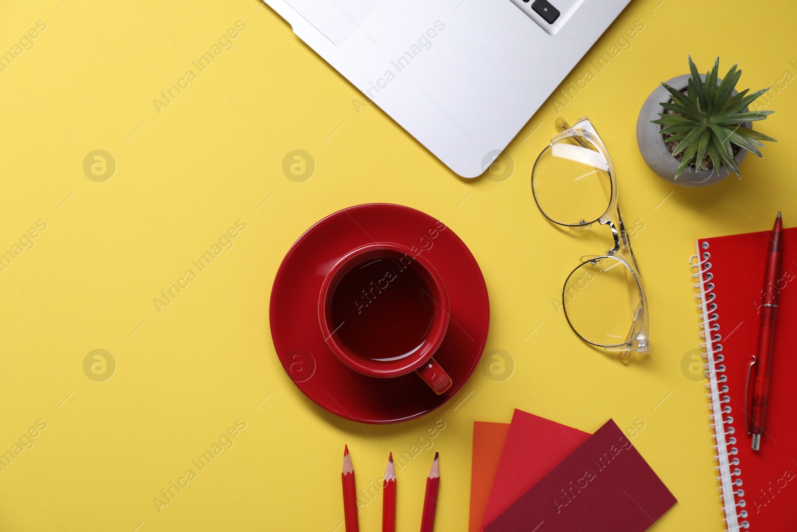 Photo of Designer's workplace. Flat lay composition with stationery, laptop and cup of coffee on yellow background, space for text