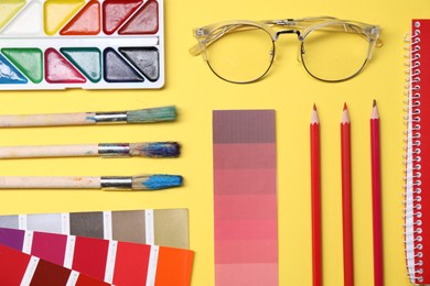 Photo of Designer's workplace. Flat lay composition with stationery and glasses on yellow background