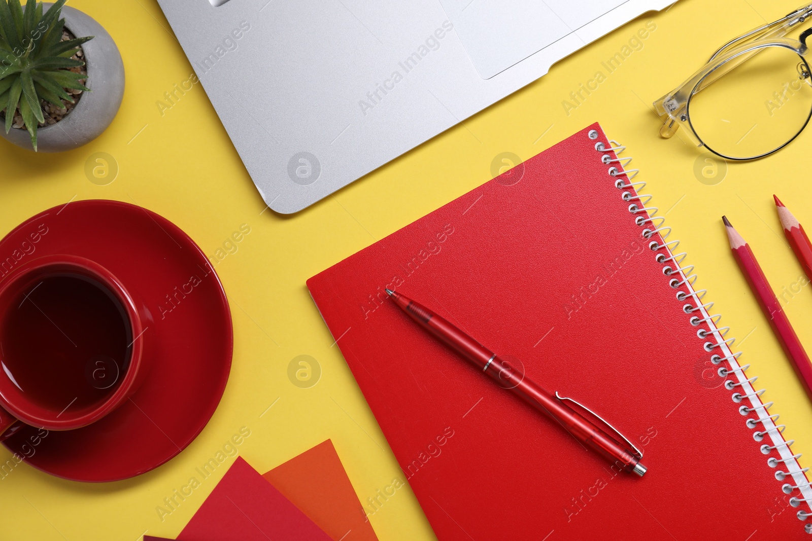 Photo of Designer's workplace. Flat lay composition with stationery, laptop and cup of coffee on yellow background