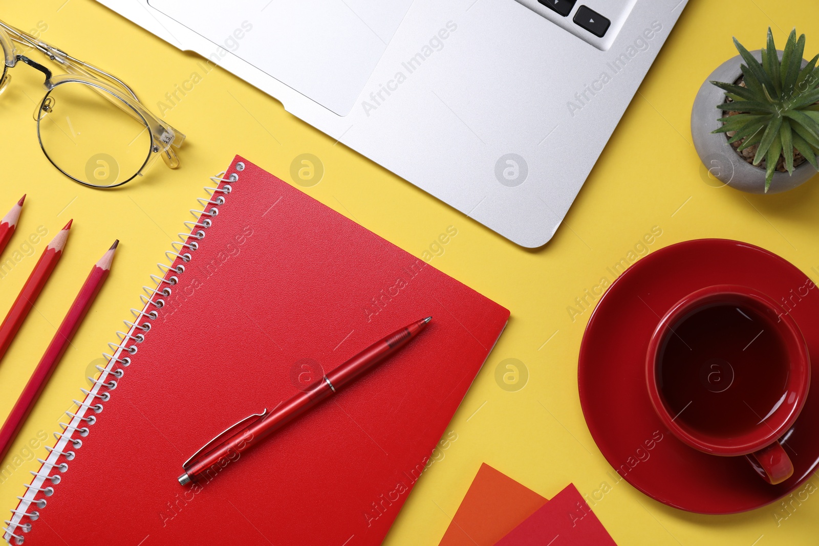 Photo of Designer's workplace. Flat lay composition with stationery, laptop and cup of coffee on yellow background