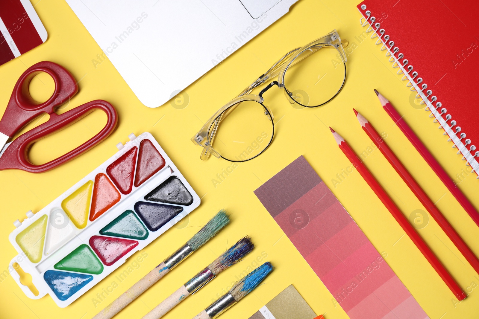 Photo of Designer's workplace. Flat lay composition with stationery and laptop on yellow background