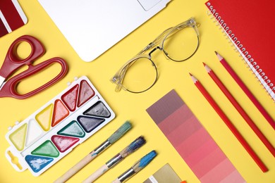 Photo of Designer's workplace. Flat lay composition with stationery and laptop on yellow background