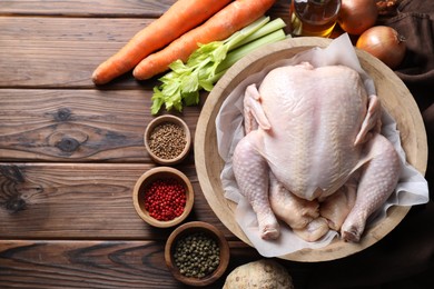 Photo of Fresh raw turkey in bowl and different products on wooden table, flat lay. Space for text