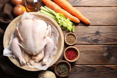 Photo of Fresh raw turkey in bowl and different products on wooden table, flat lay. Space for text