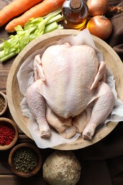 Photo of Fresh raw turkey in bowl and different products on table, flat lay