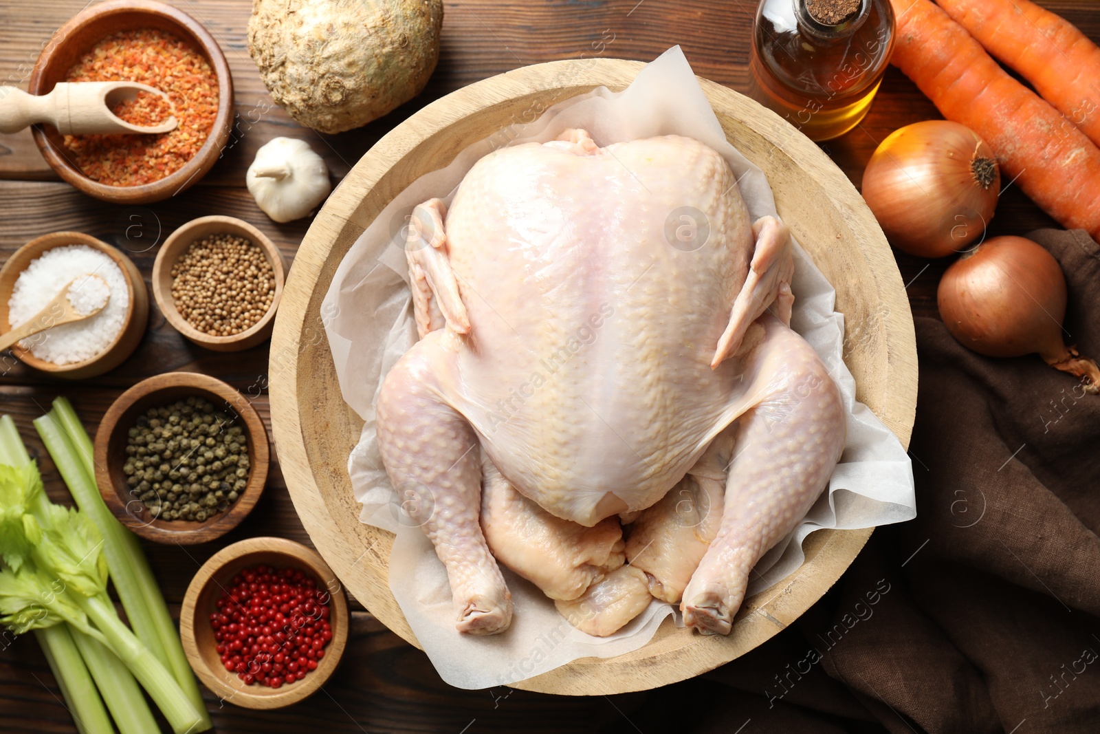 Photo of Fresh raw turkey in bowl and different products on wooden table, flat lay