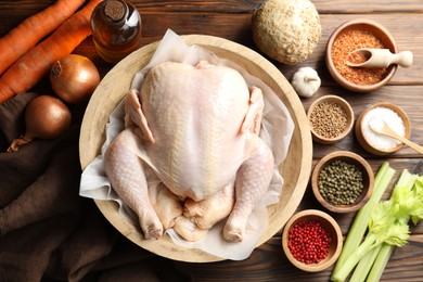 Fresh raw turkey in bowl and different products on wooden table, flat lay