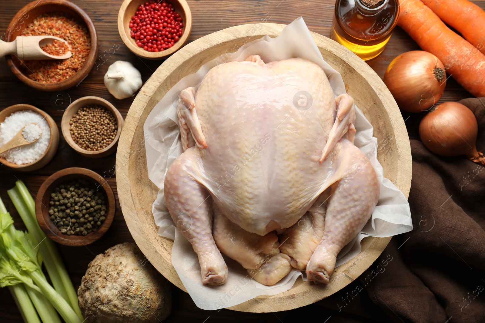 Photo of Fresh raw turkey in bowl and different products on wooden table, flat lay