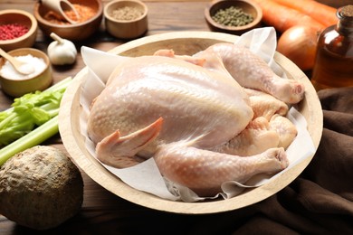 Photo of Fresh raw turkey in bowl and different products on table, closeup