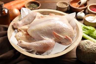 Photo of Fresh raw turkey in bowl and different products on table, closeup