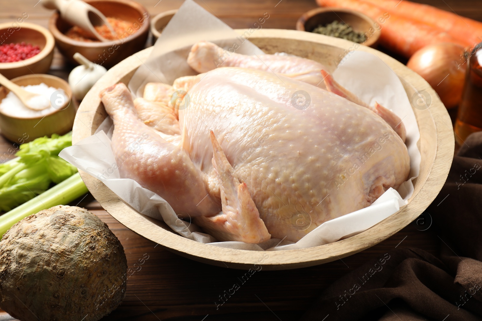 Photo of Fresh raw turkey in bowl and different products on table, closeup