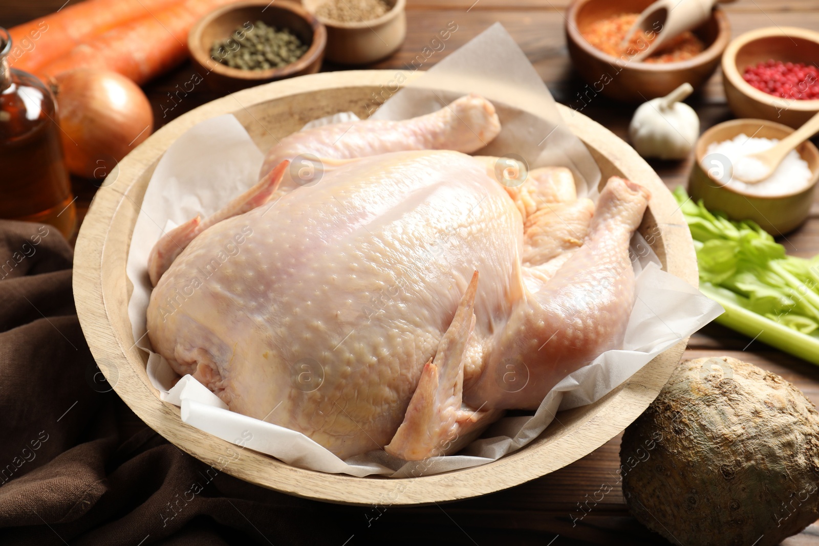 Photo of Fresh raw turkey in bowl and different products on table, closeup