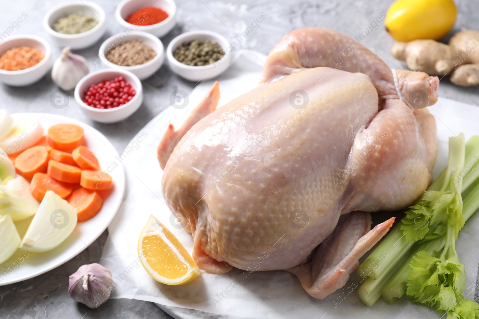 Photo of Fresh raw turkey and different products on gray textured table, closeup