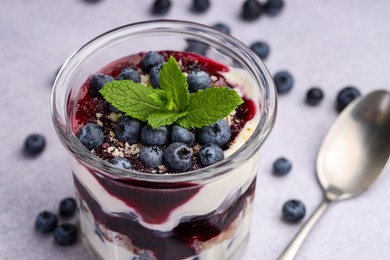 Photo of Tasty trifle dessert. Blueberries, sponge cake and whipped cream in glass on light grey table