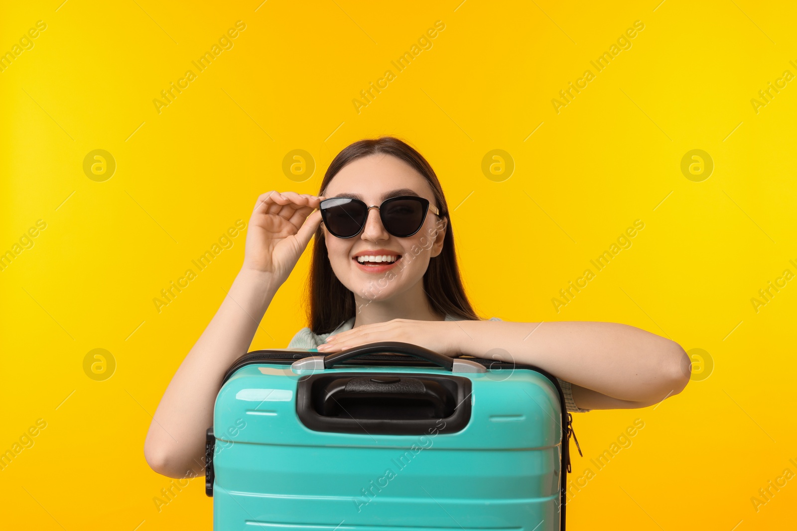 Photo of Woman with suitcase wearing sunglasses on orange background