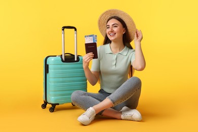 Photo of Woman with tickets, passport and suitcase on orange background