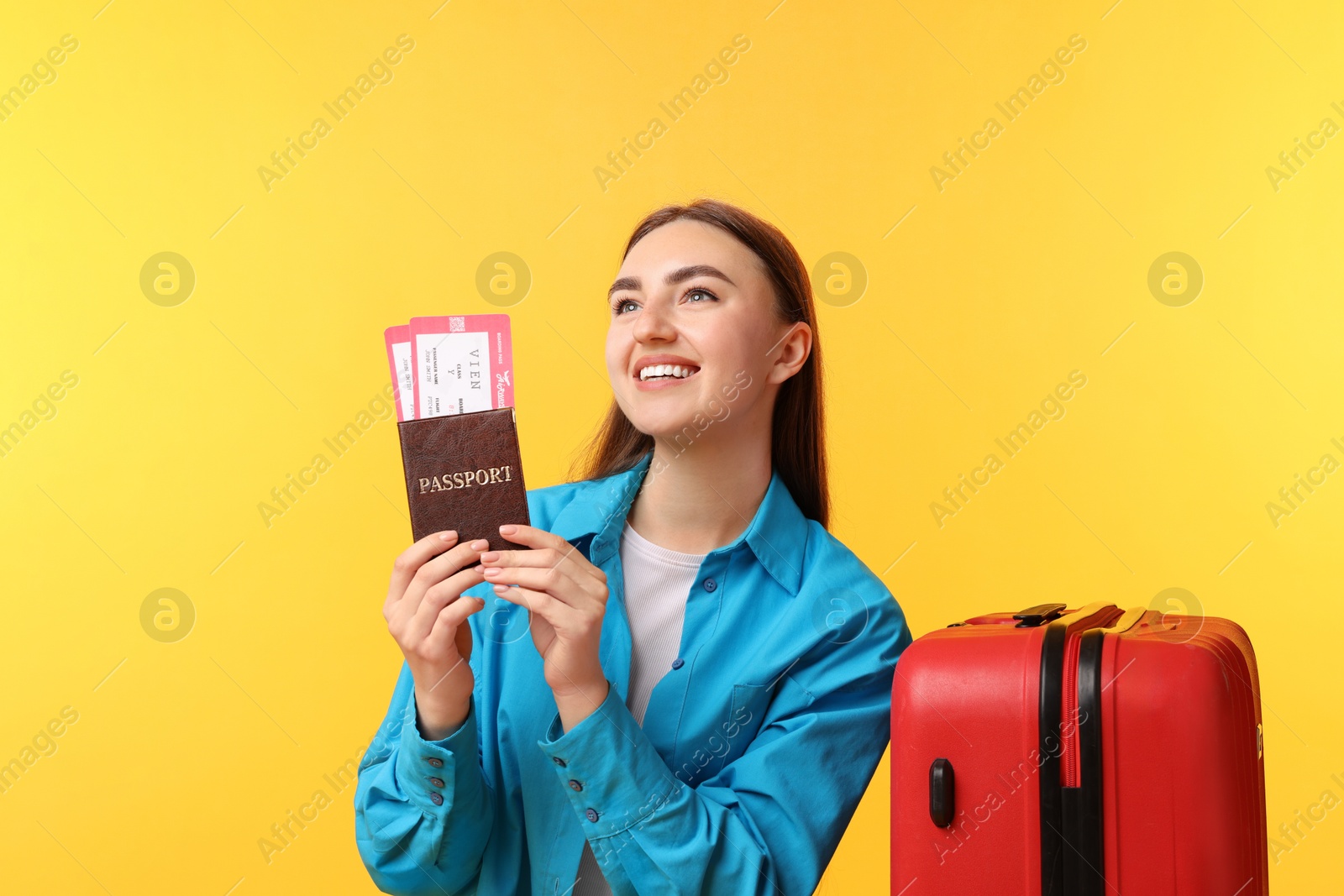 Photo of Woman with tickets, passport and suitcase on orange background