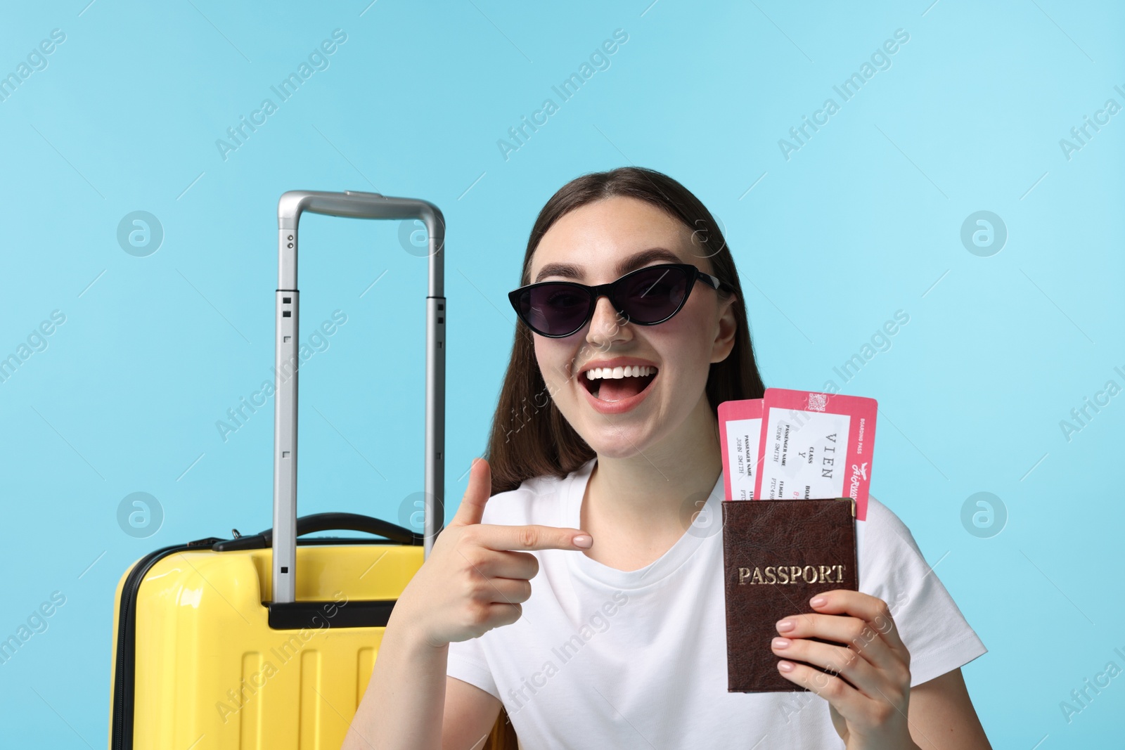 Photo of Woman with tickets, passport and suitcase on light blue background