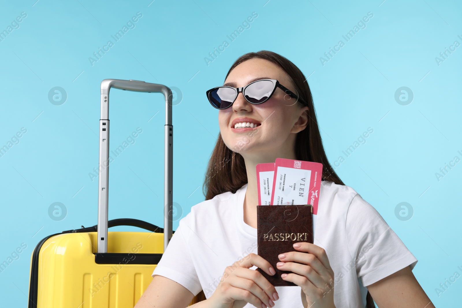 Photo of Woman with tickets, passport and suitcase on light blue background