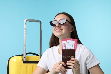 Photo of Woman with tickets, passport and suitcase on light blue background