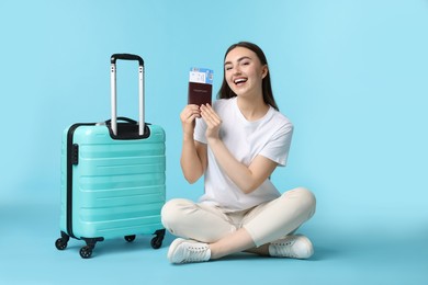 Photo of Woman with ticket, passport, and suitcase on light blue background