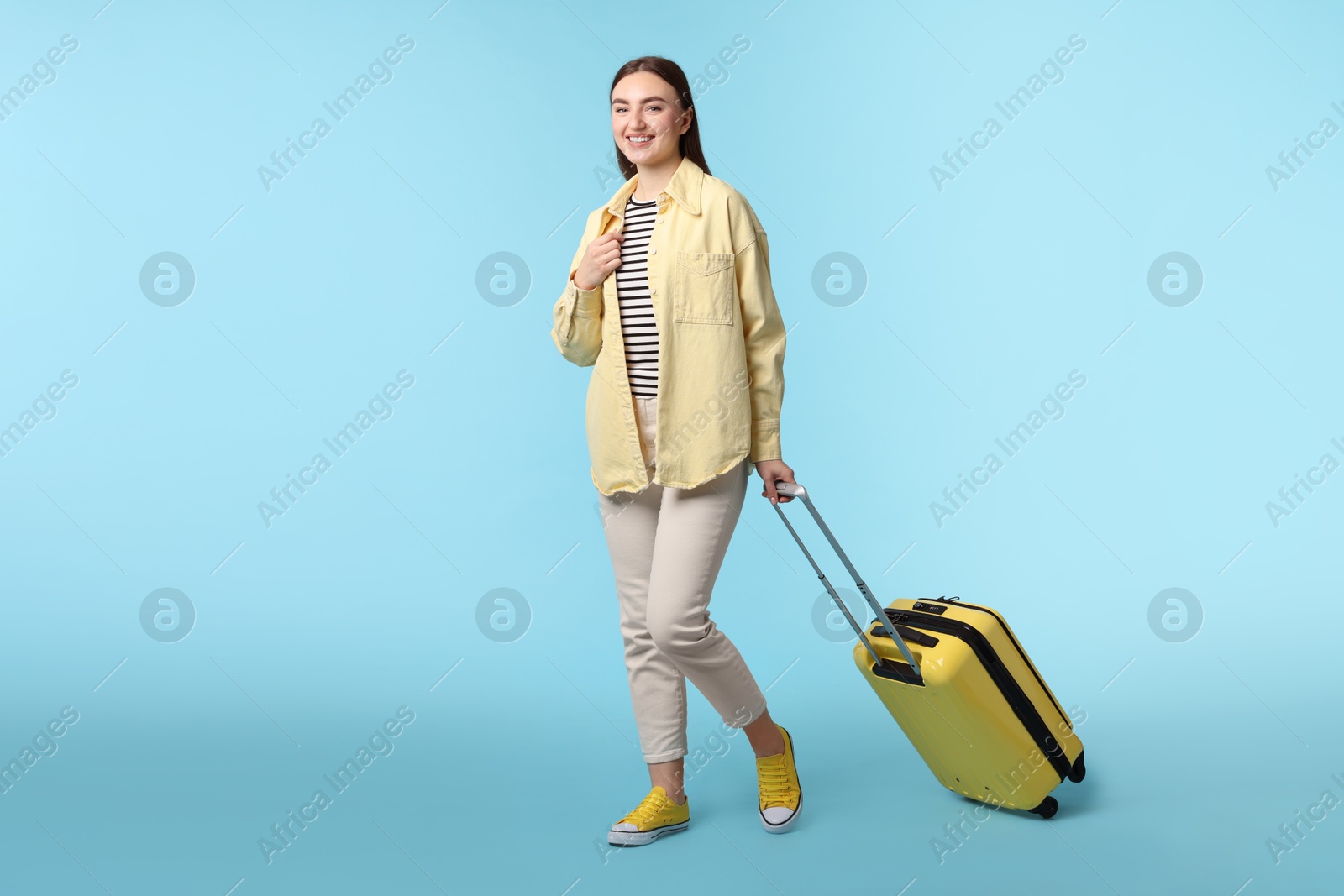 Photo of Woman with suitcase on light blue background