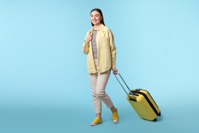 Photo of Woman with suitcase on light blue background