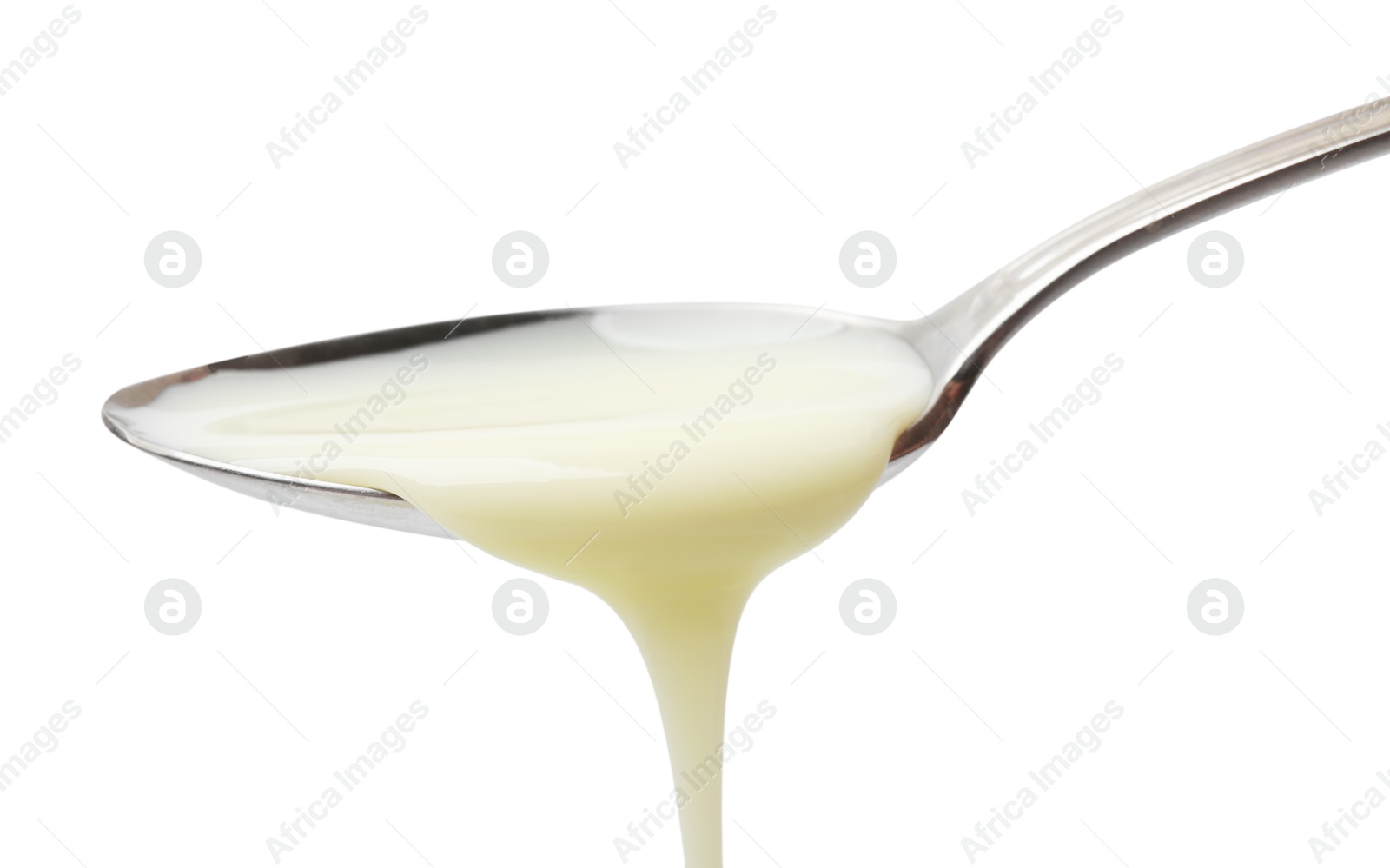 Photo of Delicious condensed milk pouring from spoon isolated on white