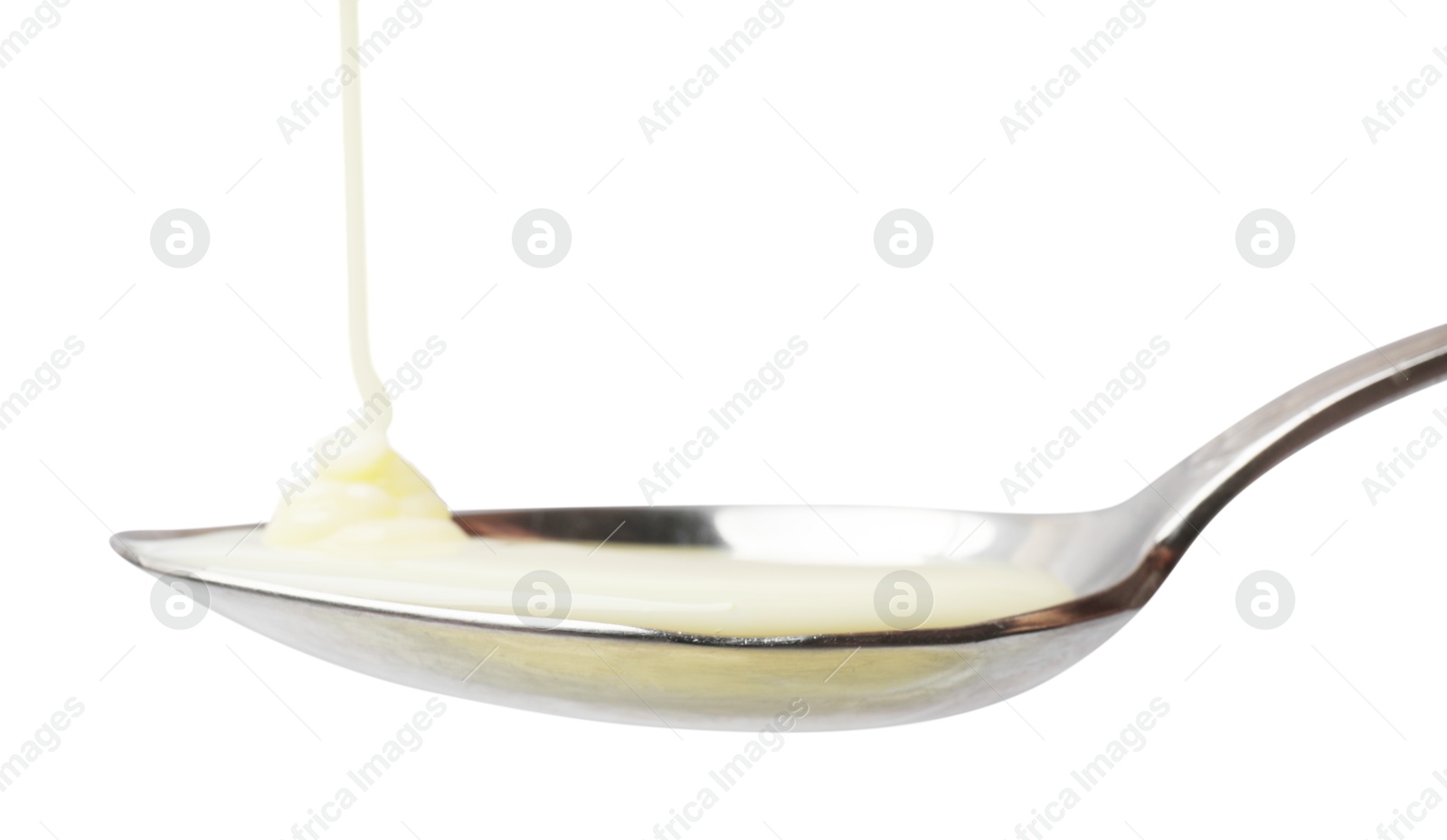 Photo of Delicious condensed milk pouring onto spoon isolated on white