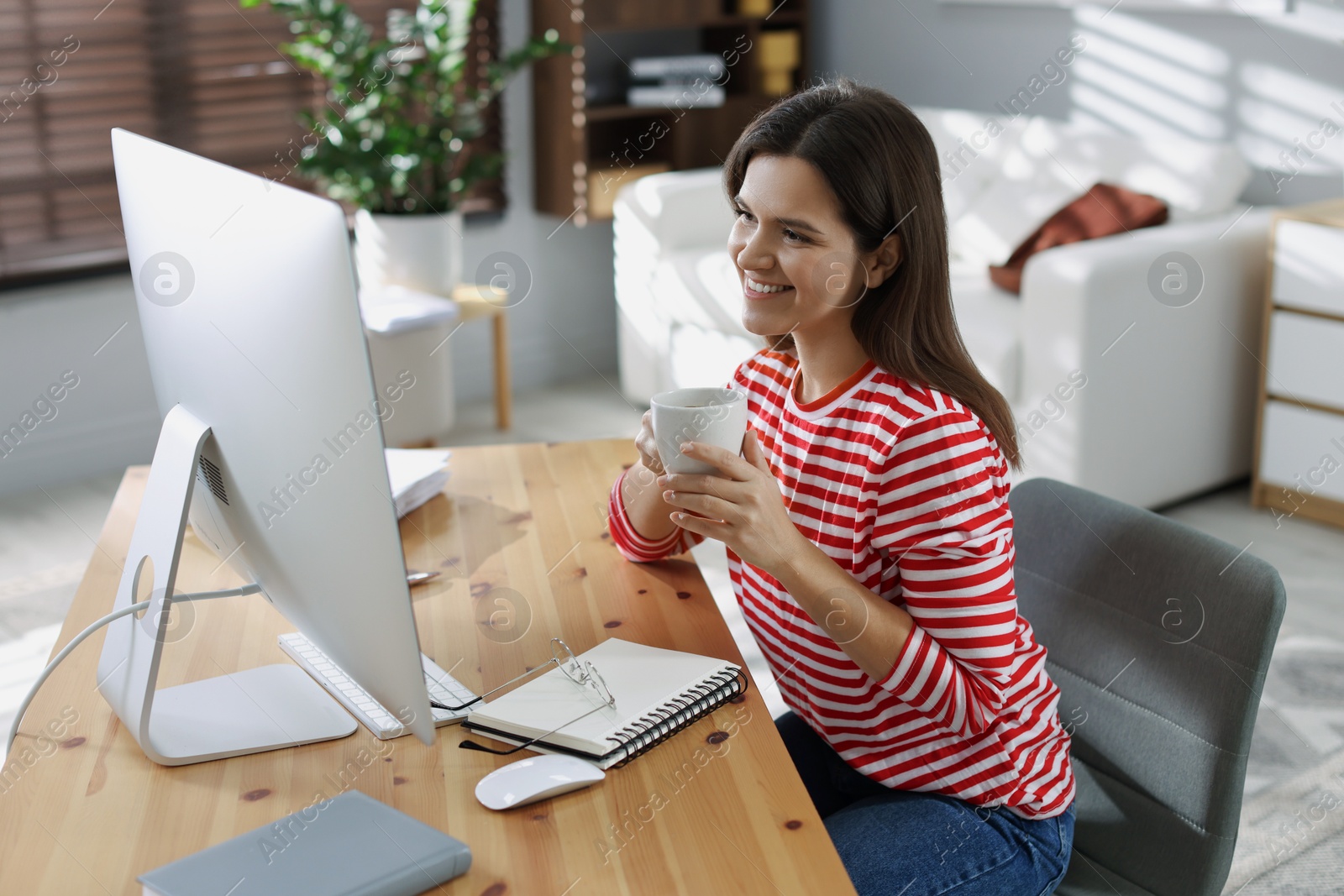 Photo of Happy woman working with computer at desk indoors. Home office