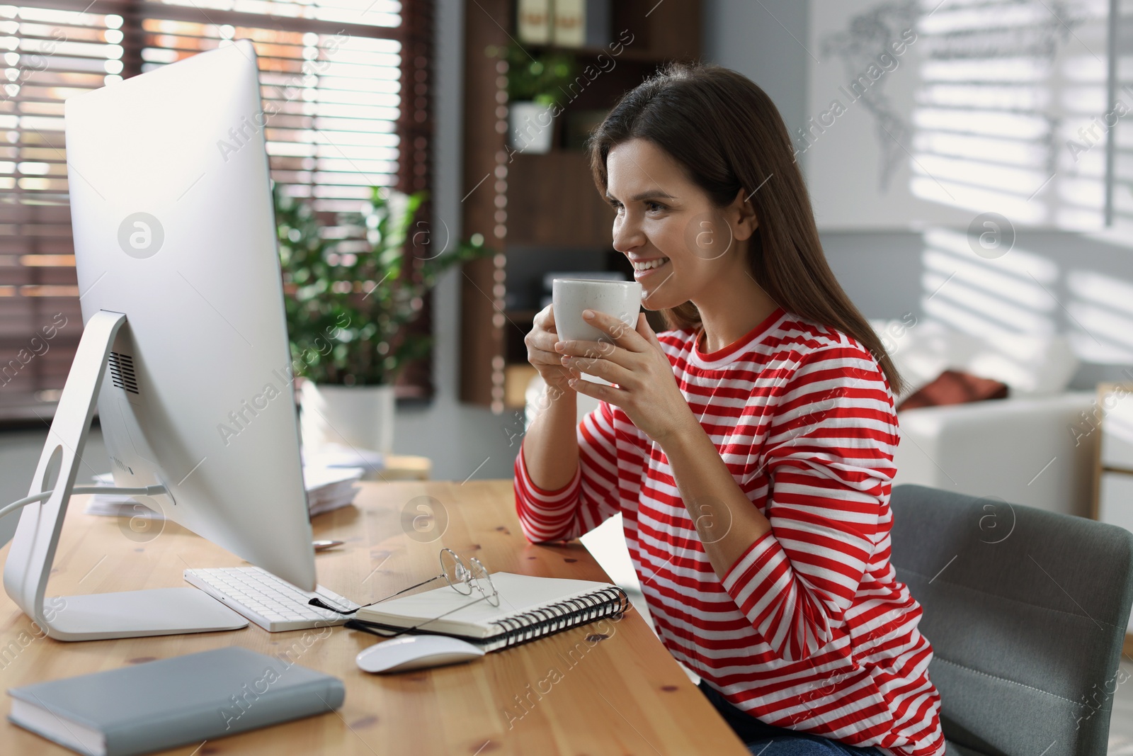 Photo of Happy woman working with computer at desk indoors. Home office