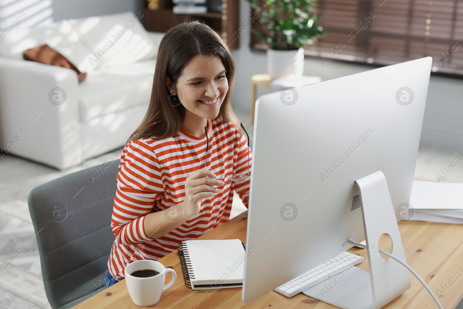 Photo of Happy woman working with computer at desk indoors. Home office