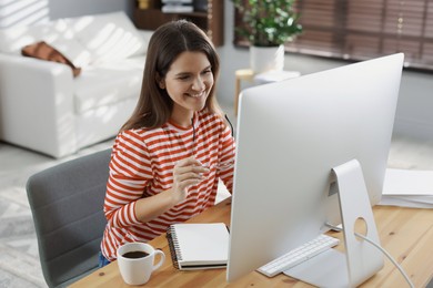 Photo of Happy woman working with computer at desk indoors. Home office