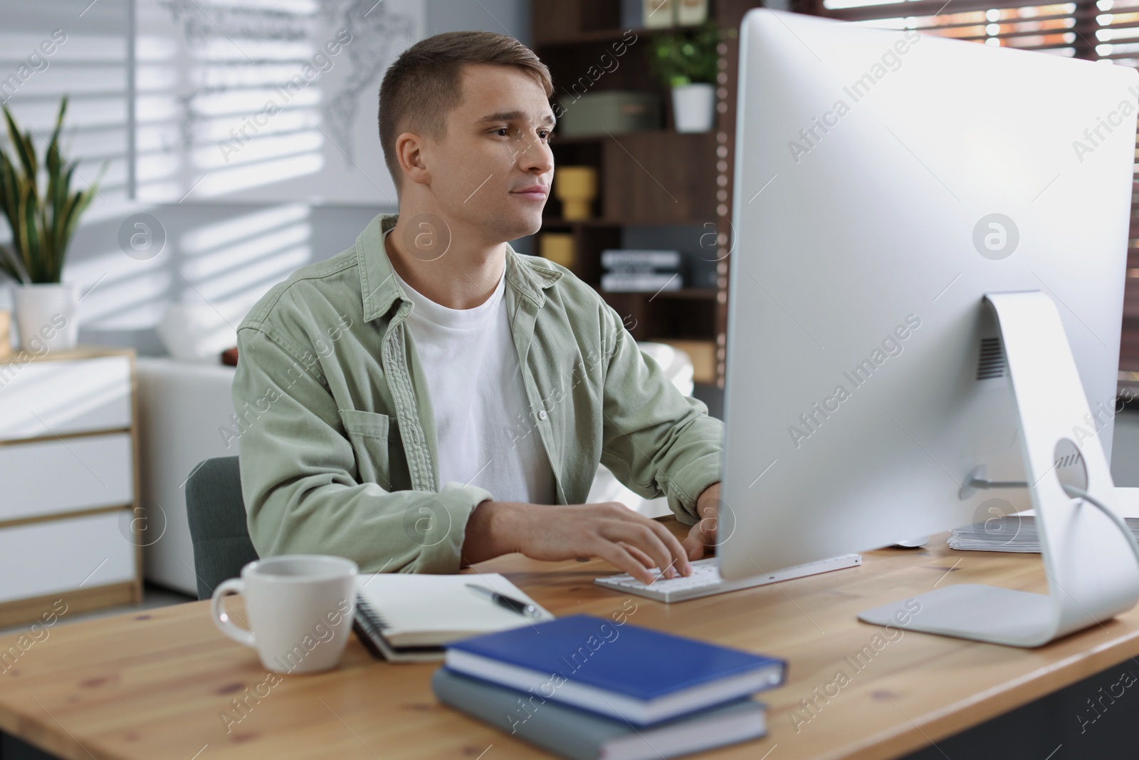 Photo of Handsome man working with computer at desk indoors. Home office