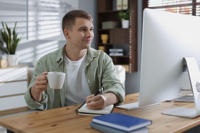 Photo of Handsome man working with computer at desk indoors. Home office