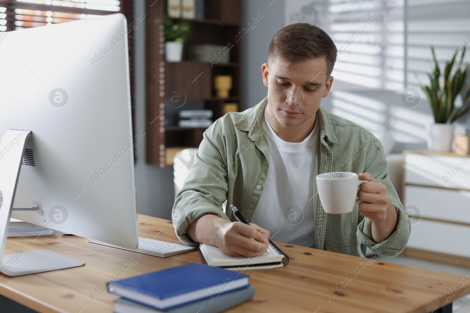 Photo of Handsome man working with computer at desk indoors. Home office